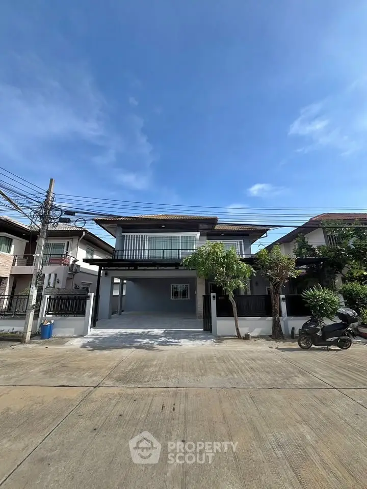 Modern two-story house with spacious driveway and lush greenery under a clear blue sky.