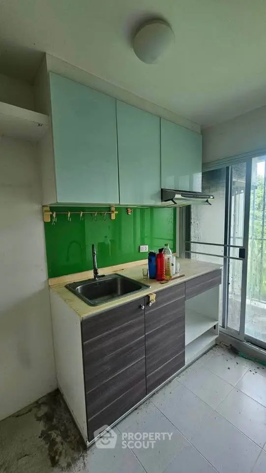 Modern compact kitchen with sleek cabinetry and green backsplash, featuring a large window for natural light.