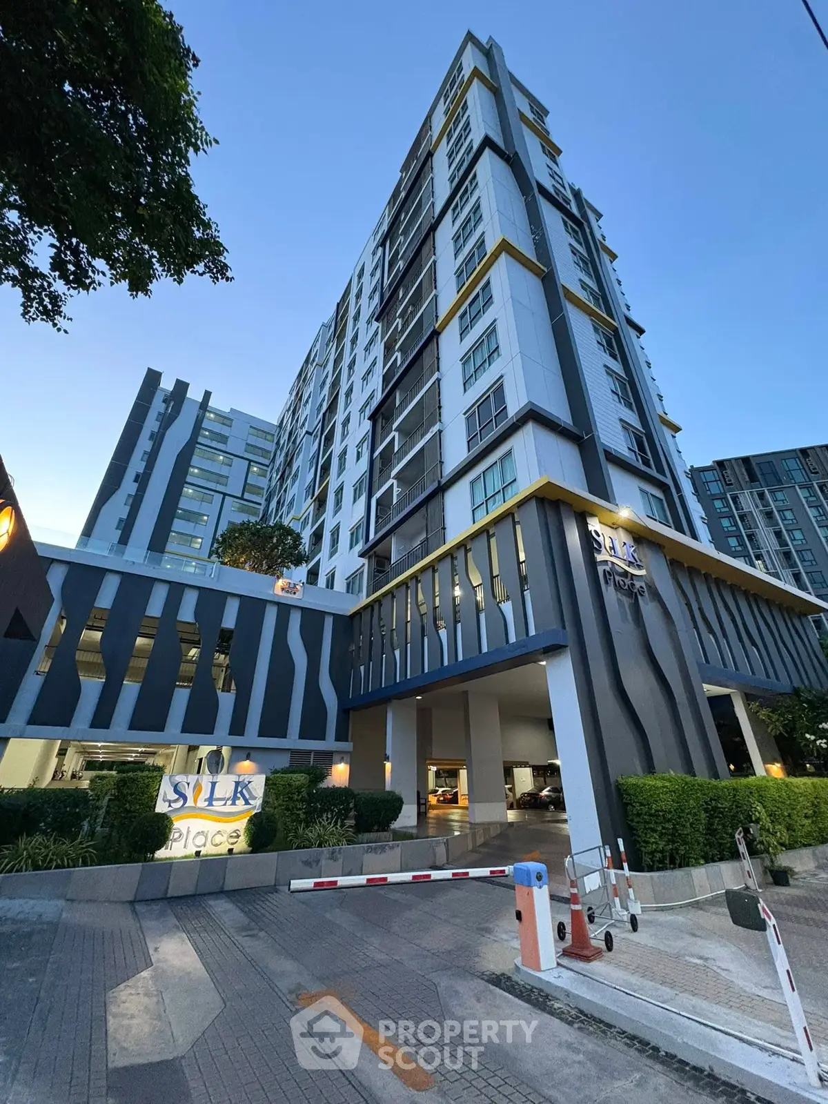 Modern high-rise condominium with sleek design and lush greenery at Silk Place.