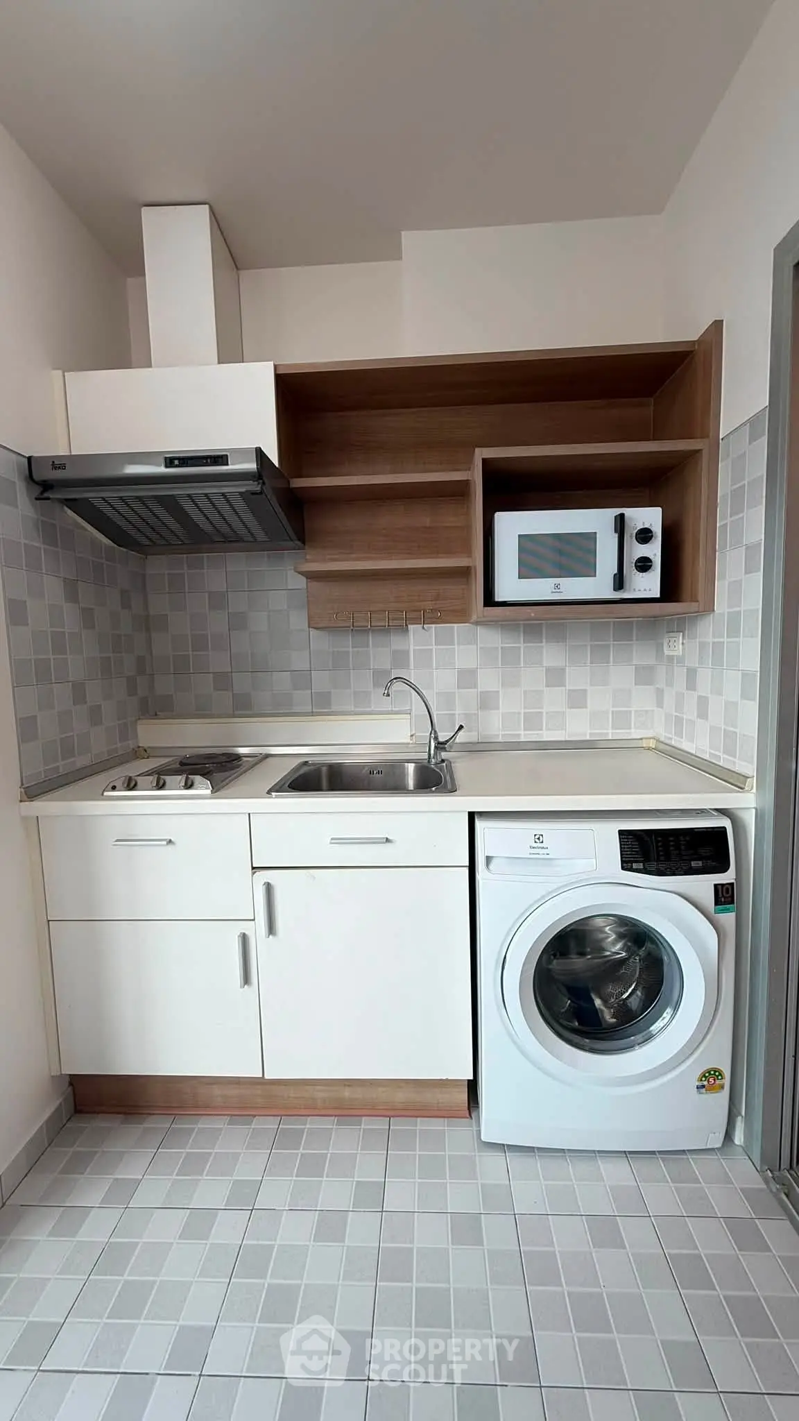 Modern compact kitchen with washing machine and microwave, ideal for urban living.