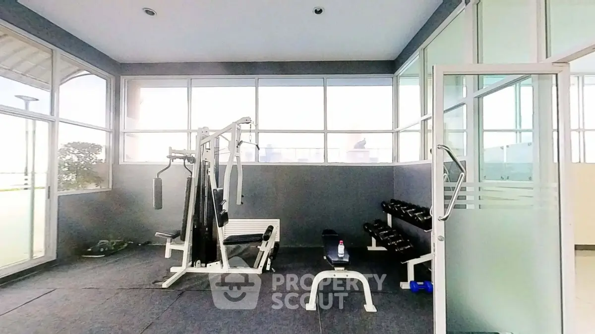 Modern gym with fitness equipment and large windows in a residential building.