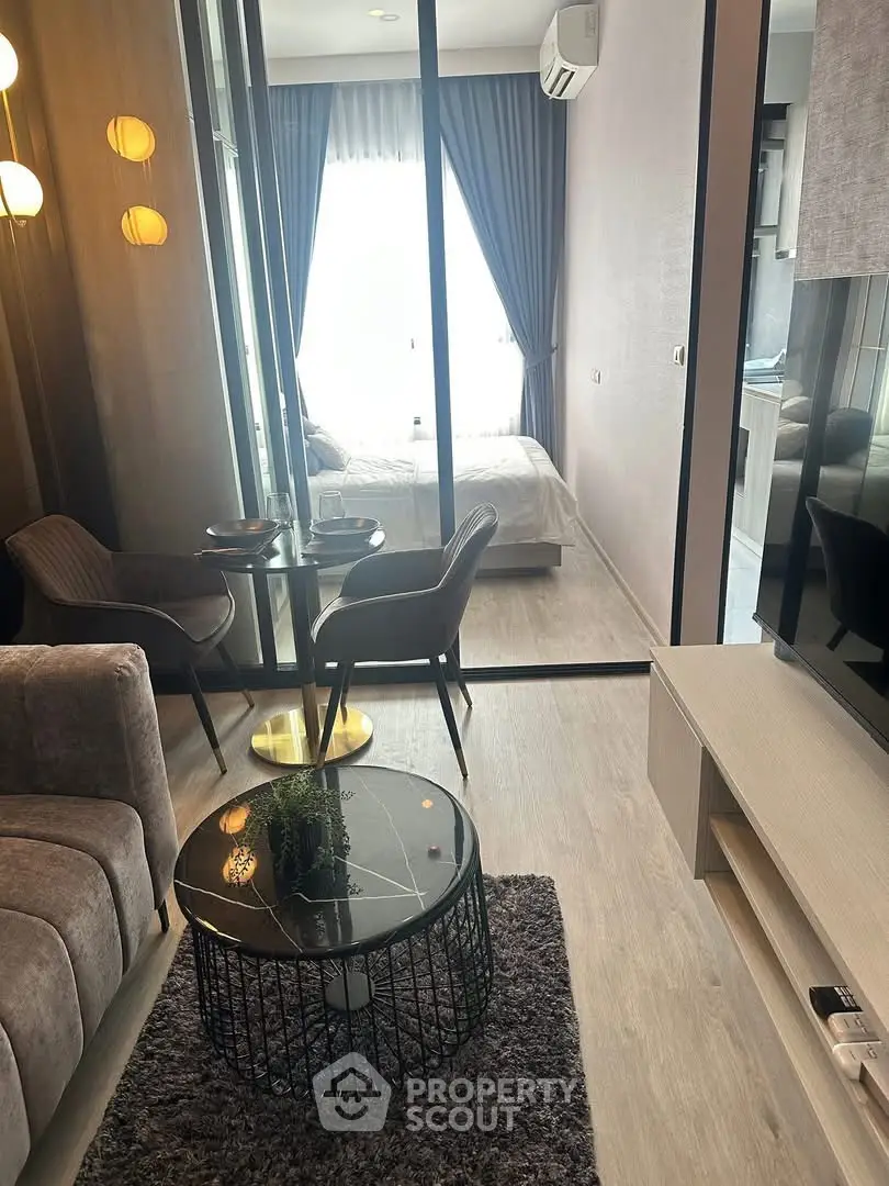 Modern living room with glass partition leading to cozy bedroom
