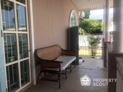 Charming porch with classic wicker bench and elegant arched window, perfect for relaxing outdoors.