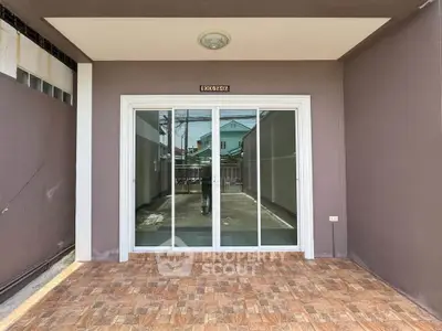 Spacious patio with sliding glass doors and tiled flooring, perfect for outdoor relaxation.
