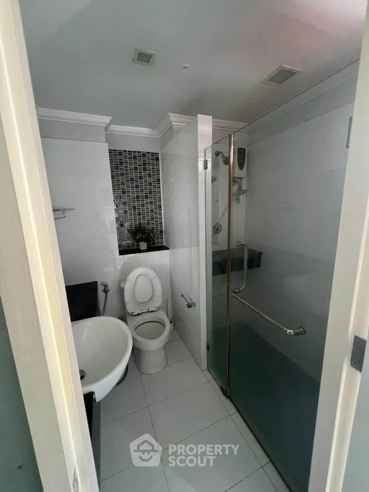 Modern bathroom with glass shower and sleek tile design, perfect for urban living.