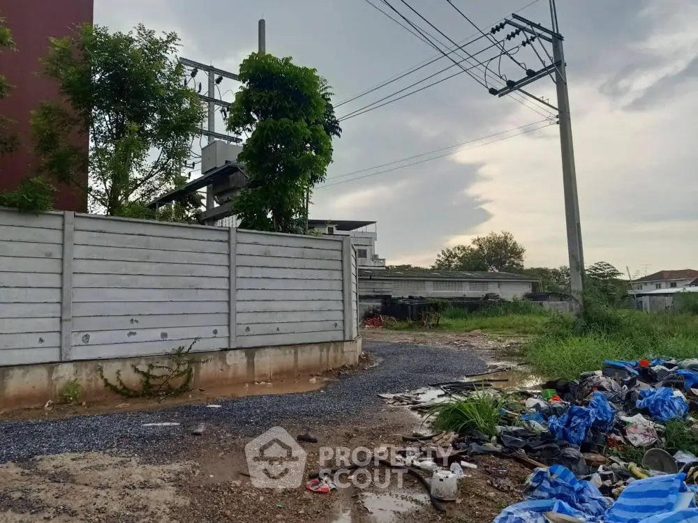 Vacant land with potential for development, featuring utility access and partial fencing.