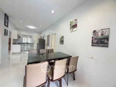 Spacious dining area with modern kitchen in open layout, featuring elegant decor and ample natural light.