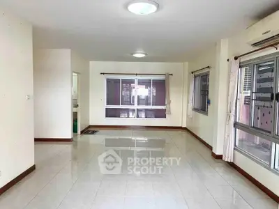 Spacious empty living room with large windows and tiled flooring, perfect for customization.