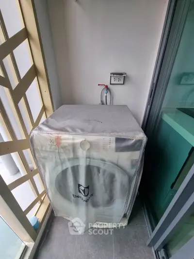 Compact balcony with washing machine and modern railing design.