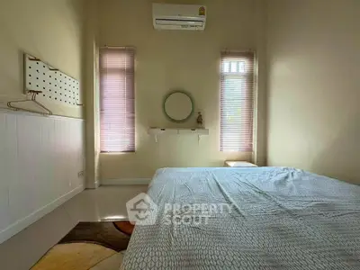 Cozy bedroom with minimalist decor and natural light, featuring a comfortable bed and air conditioning.