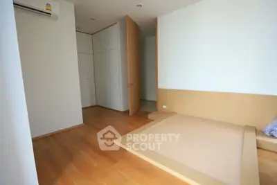 Spacious minimalist bedroom with wooden flooring and built-in wardrobe