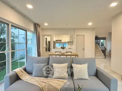 Modern living room with open layout and stylish decor, featuring a cozy sofa and dining area.