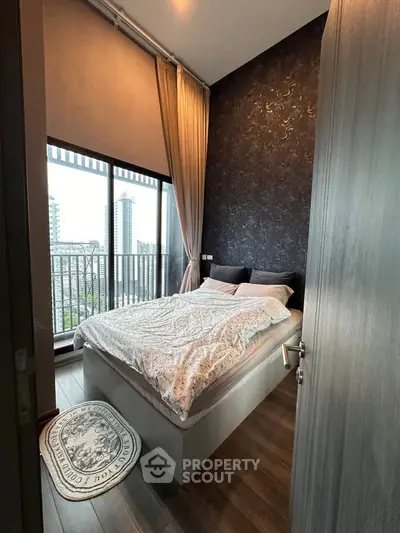 Modern bedroom with large window and city view, featuring elegant decor and cozy bedding.