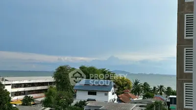 Stunning ocean view from a high-rise building overlooking lush greenery and rooftops.
