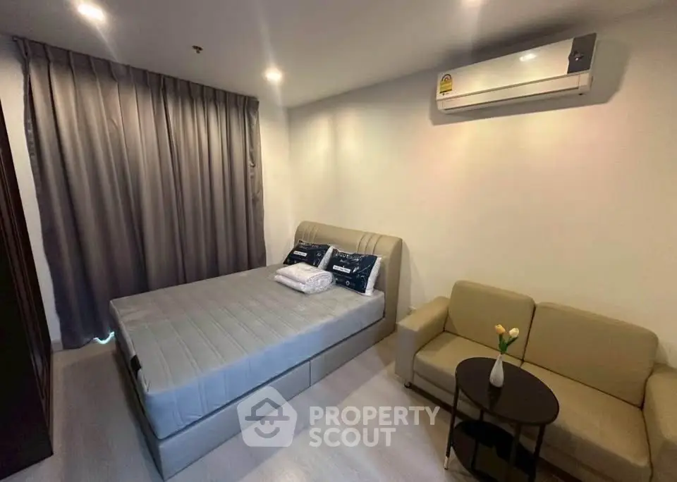 Cozy bedroom with modern decor, featuring a comfortable bed, sofa, and air conditioning.