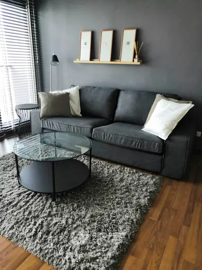 Modern living room with gray sofa, glass coffee table, and stylish decor.