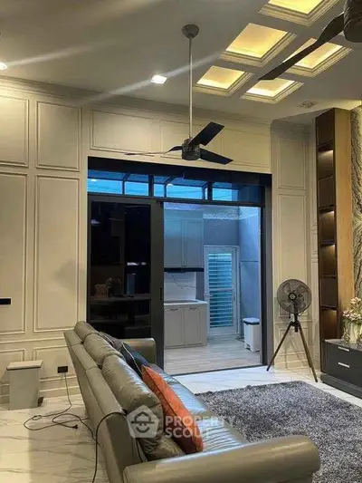 Luxurious living room with modern ceiling fan and elegant lighting, featuring a stylish open layout to the kitchen.