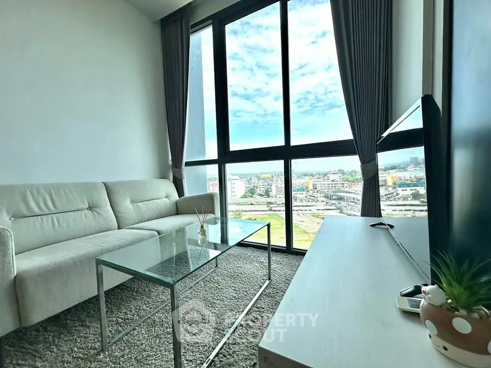Modern living room with large windows offering stunning city views and elegant furnishings.