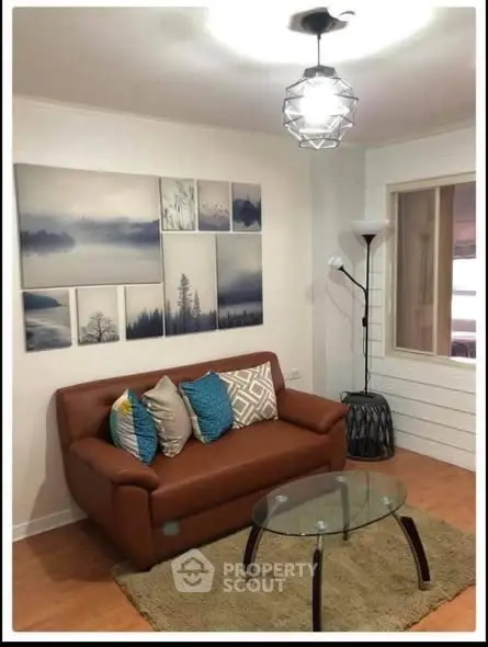 Cozy living room with modern decor, brown leather sofa, glass coffee table, and stylish wall art.