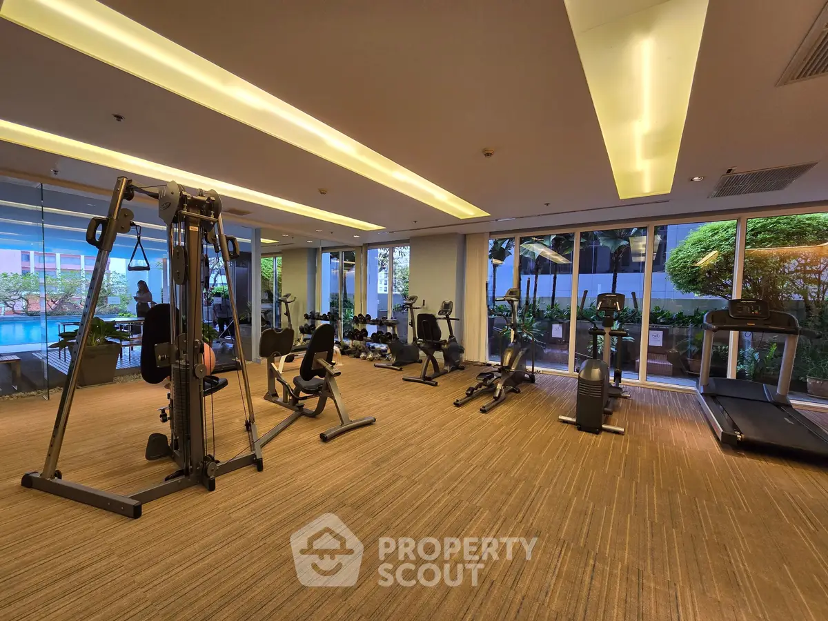 Spacious gym with modern equipment and garden view in luxury apartment complex.