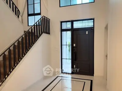 Elegant modern entrance with stylish staircase and sleek black door