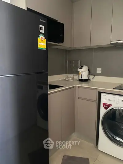 Modern kitchen with sleek appliances and compact design, featuring a washing machine and refrigerator.