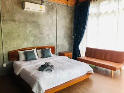 Modern bedroom with concrete walls, stylish bed, and natural light from large window.