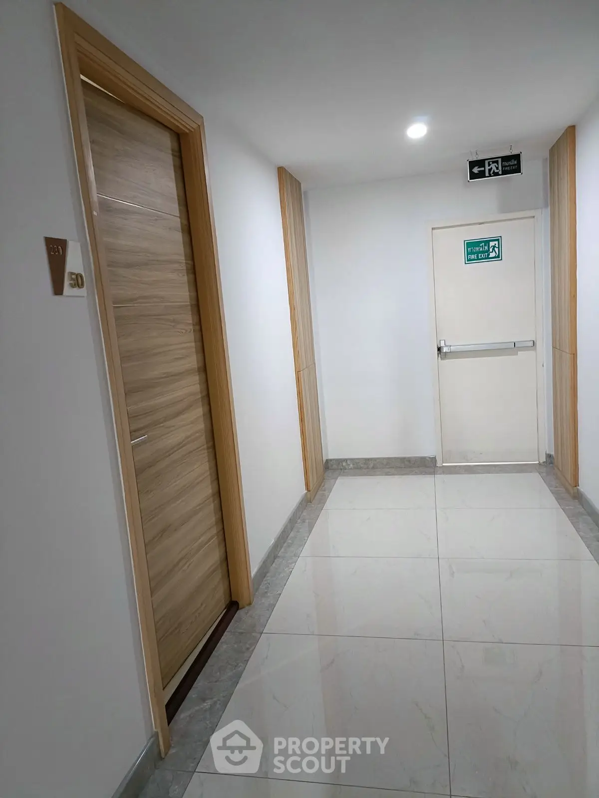 Modern apartment hallway with sleek wooden doors and polished tile flooring.