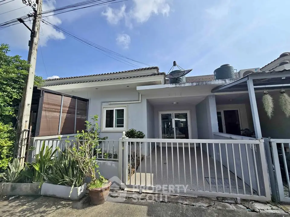 Charming single-story home with gated entrance and lush greenery.