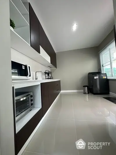 Modern kitchen with sleek cabinetry and built-in appliances, featuring a minimalist design and ample natural light.