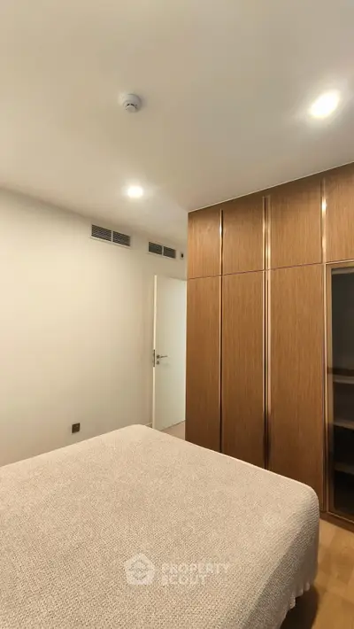 Modern bedroom with sleek wooden wardrobe and cozy bed