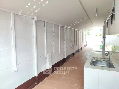 Spacious outdoor kitchen area with tiled flooring and modern sink setup.