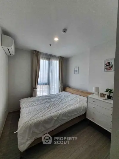 Cozy bedroom with modern decor and large window offering natural light.