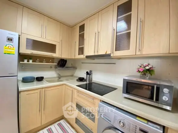 Modern kitchen with wooden cabinets, stainless steel appliances, and cozy decor.