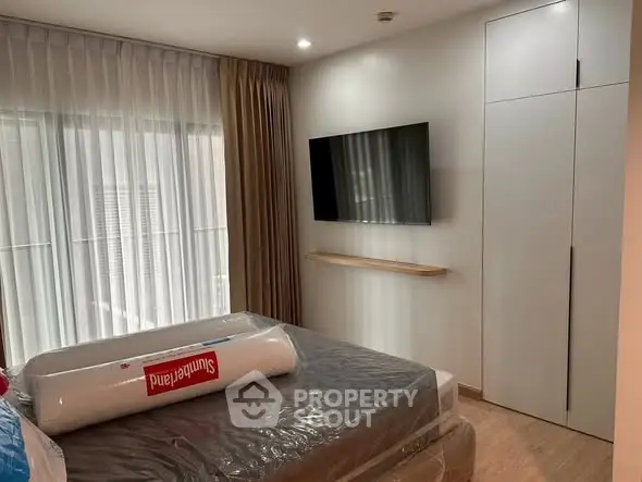 Modern bedroom with wall-mounted TV and floor-to-ceiling window for natural light.