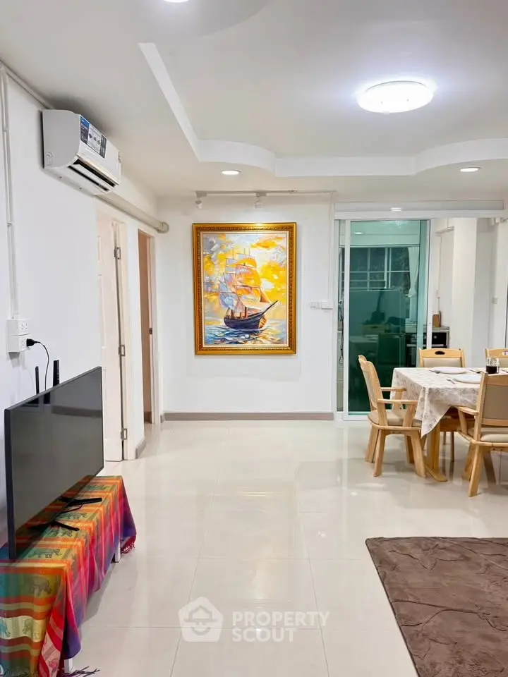 Spacious living room with modern decor and dining area, featuring a vibrant painting and sleek furniture.