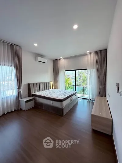 Spacious bedroom with large windows and balcony access, featuring modern furnishings and elegant decor.