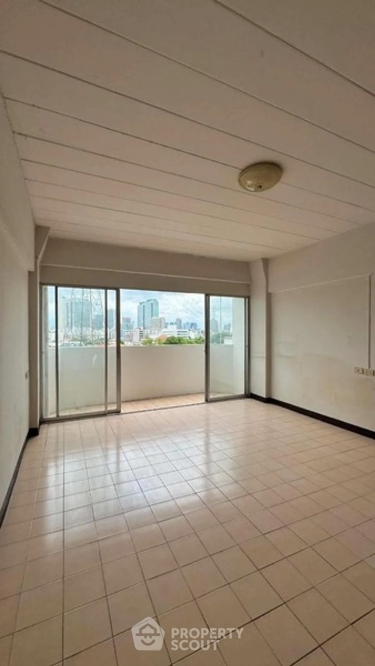 Spacious living room with large windows offering a stunning city view, perfect for urban living.