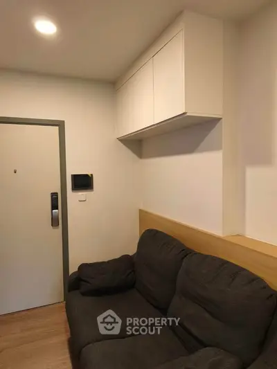 Cozy living room with modern sofa and wall-mounted storage in a compact apartment.