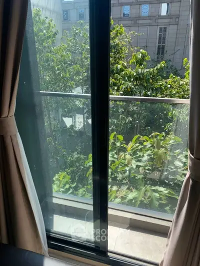 Charming balcony view with lush greenery from a modern apartment window.