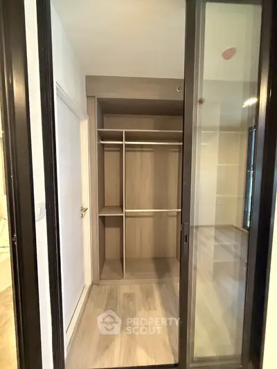 Modern walk-in closet with sliding glass doors and wooden shelves