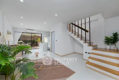 Modern living room with staircase and open layout, featuring stylish decor and natural light.