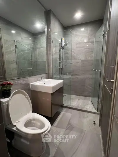 Modern bathroom with glass shower and sleek fixtures in contemporary design.