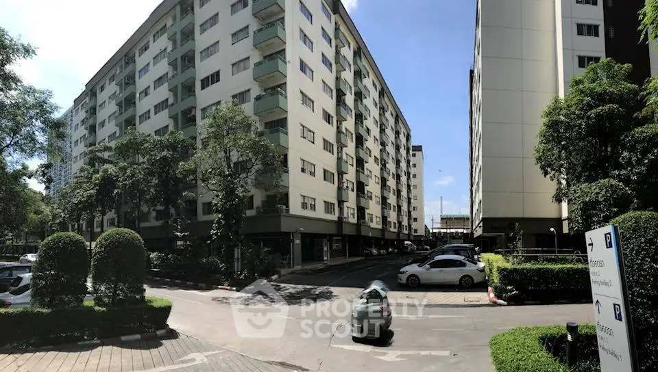 Modern apartment complex with lush greenery and ample parking space, ideal for urban living.