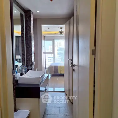 Modern apartment interior with bathroom and bedroom view, featuring sleek design and cityscape through large windows.