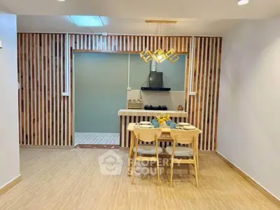 Modern kitchen with stylish dining area and unique lighting fixtures.