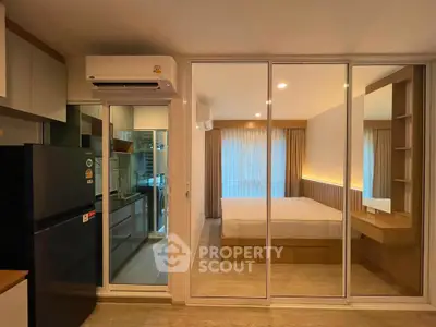 Modern studio apartment with glass partition, featuring a cozy bedroom and sleek kitchen area.