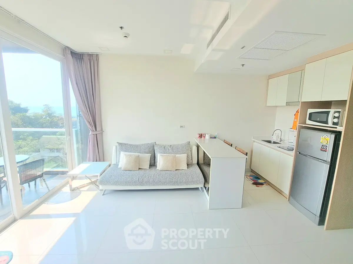 Bright modern living room with open kitchen and large windows offering scenic views.