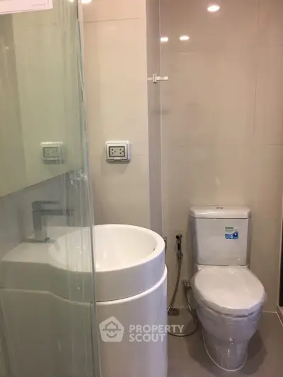 Modern bathroom with sleek fixtures and compact design, featuring a shower and toilet.