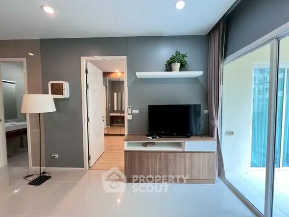 Modern living room with sleek TV stand and sliding glass doors to balcony.